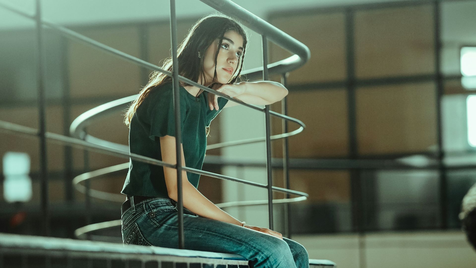 A person sitting on a stair rail in a building
