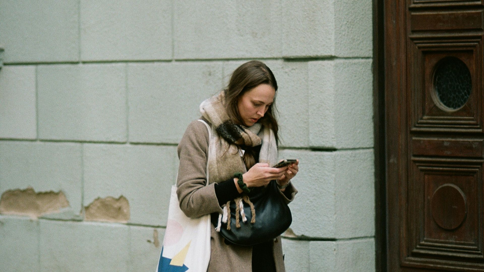A woman standing on a sidewalk looking at her cell phone