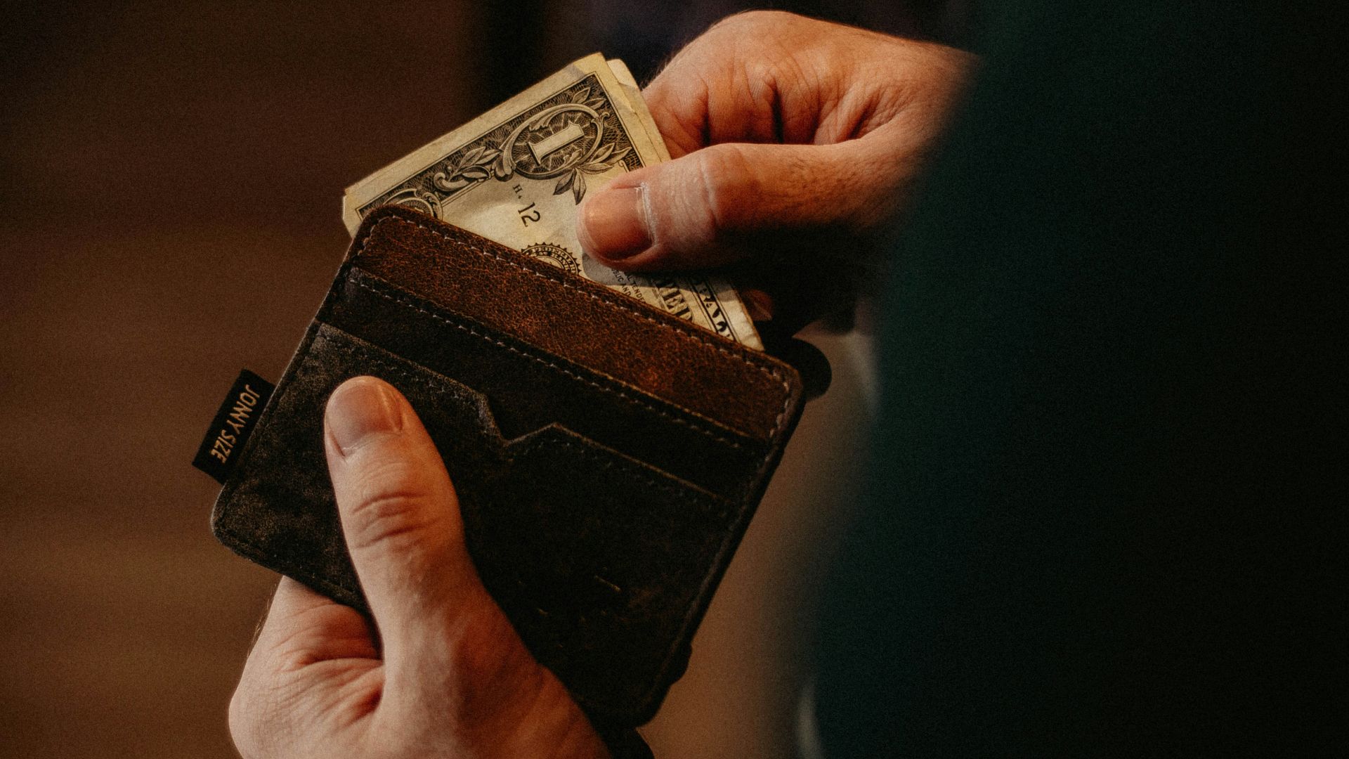 person getting 1 U.S. dollar banknote in wallet