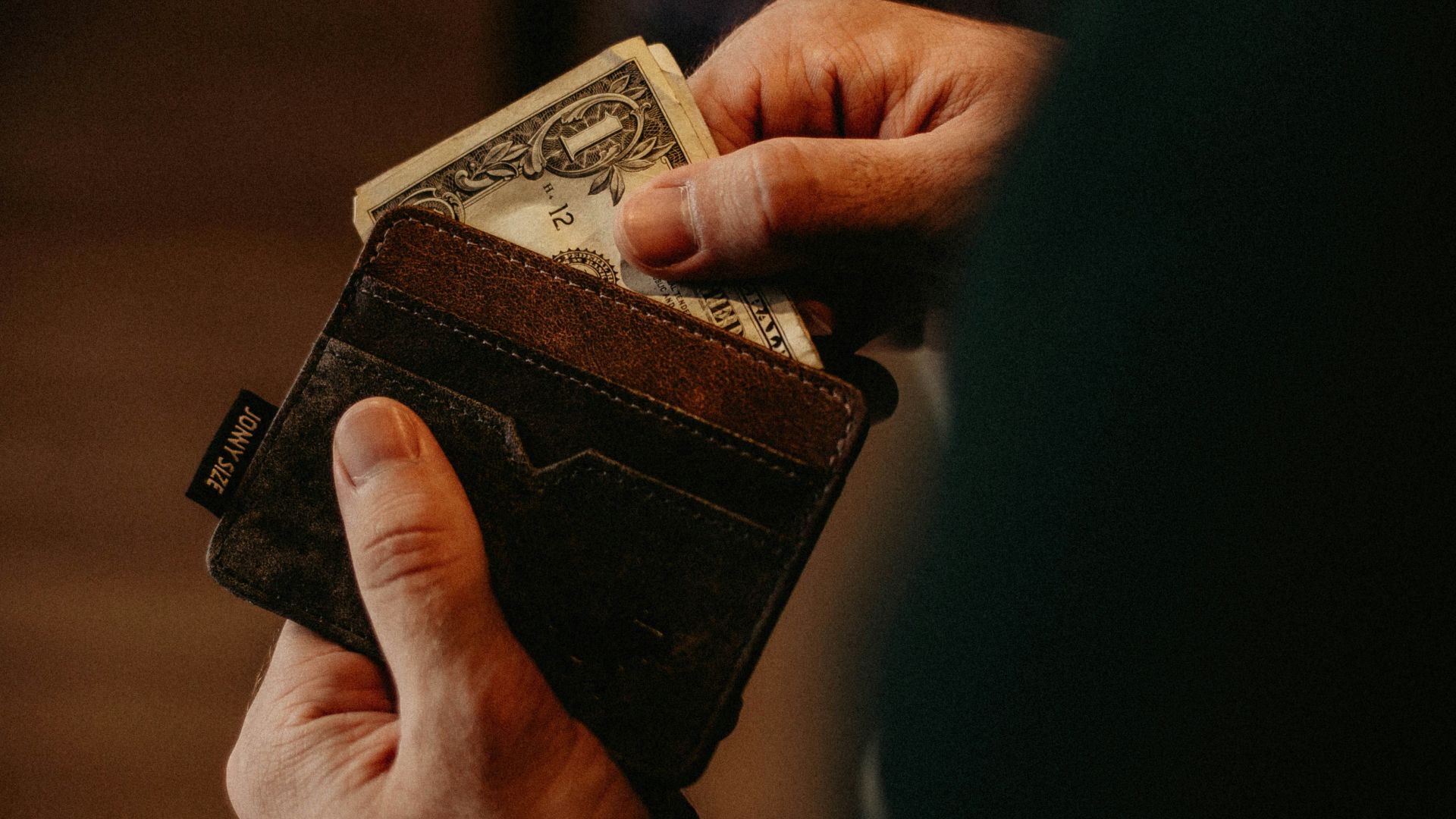 person getting 1 U.S. dollar banknote in wallet