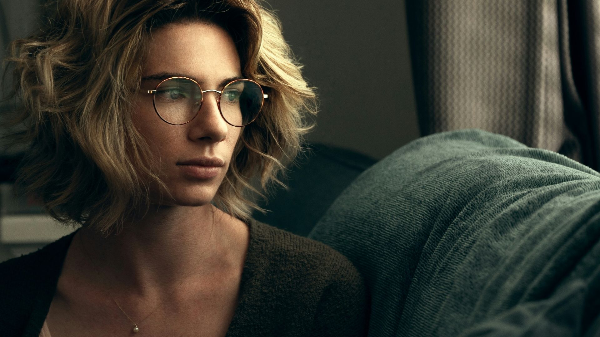 a woman wearing glasses sitting on a couch