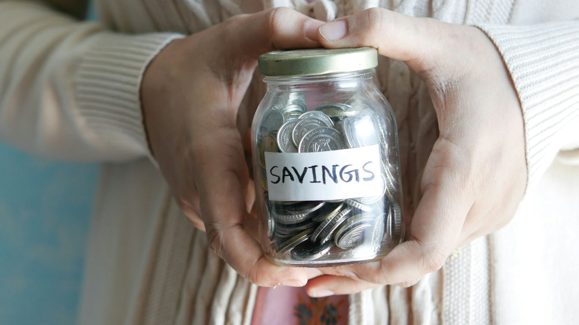 a woman holding a jar with savings written on it