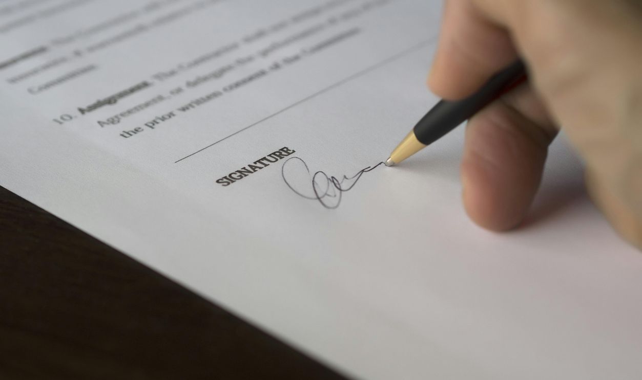 Selective Focus Photography of Person Signing on Paper