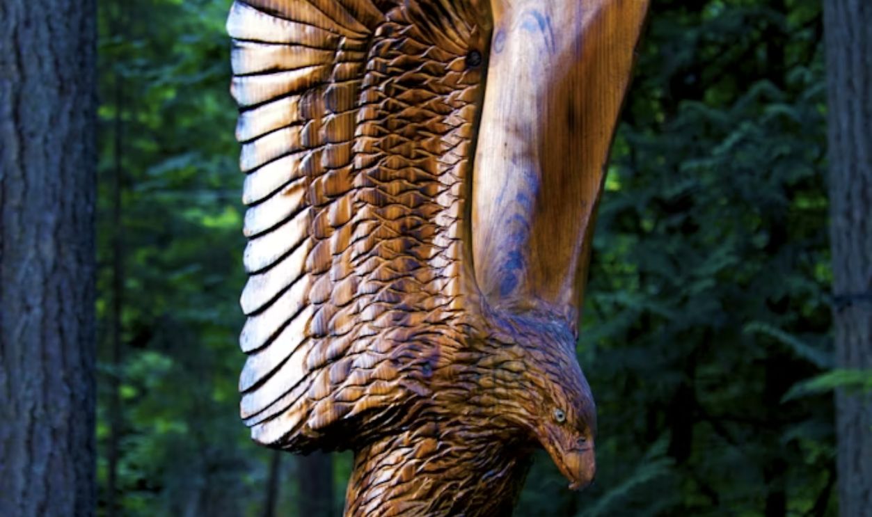 a statue of an eagle is in the middle of a forest