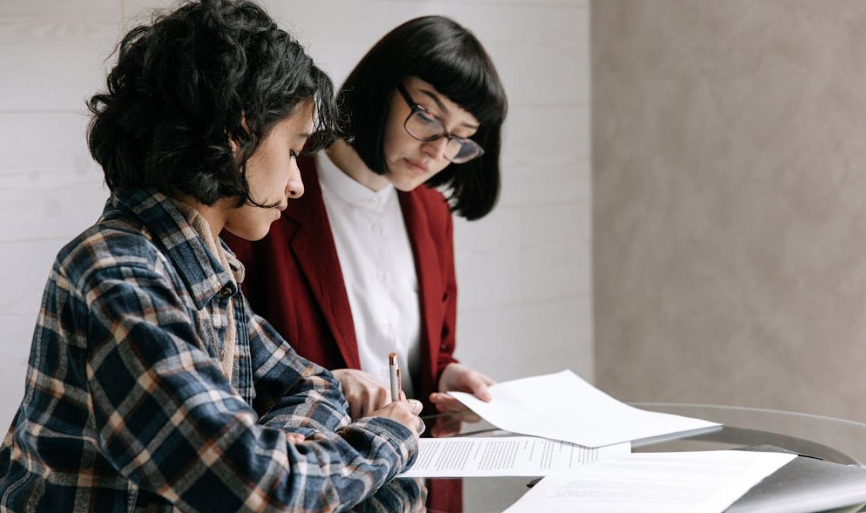 A Woman Signing a Document with Her Real Estate Agent