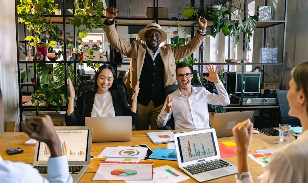 People in Office Sitting by Desk Celebrating