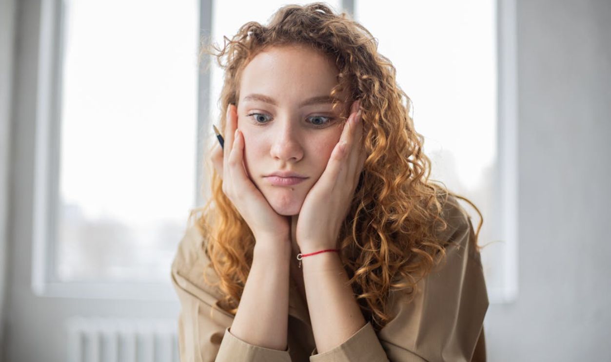 Puzzled woman with pen studying in room