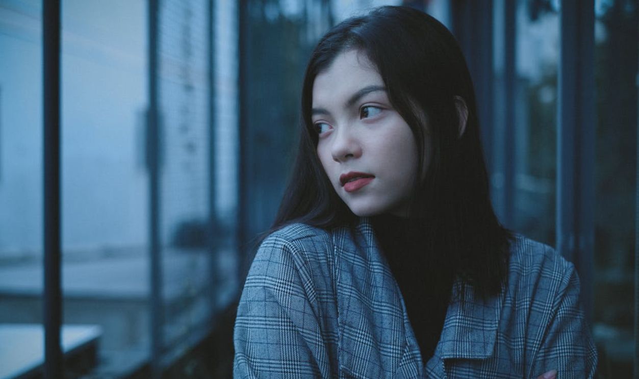Pensive teen sitting near window and contemplating