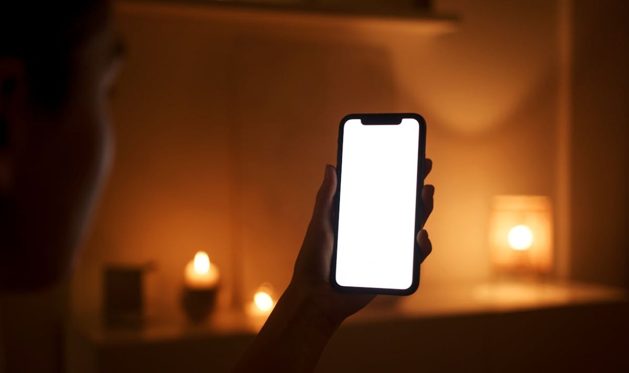 Person in the Dark Room Holding Smartphone