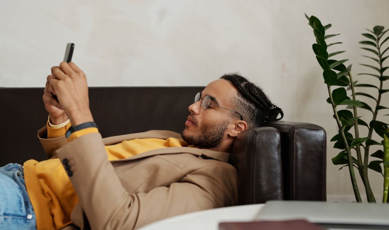 Close-up Photo of Man lying on a Black Sofa
