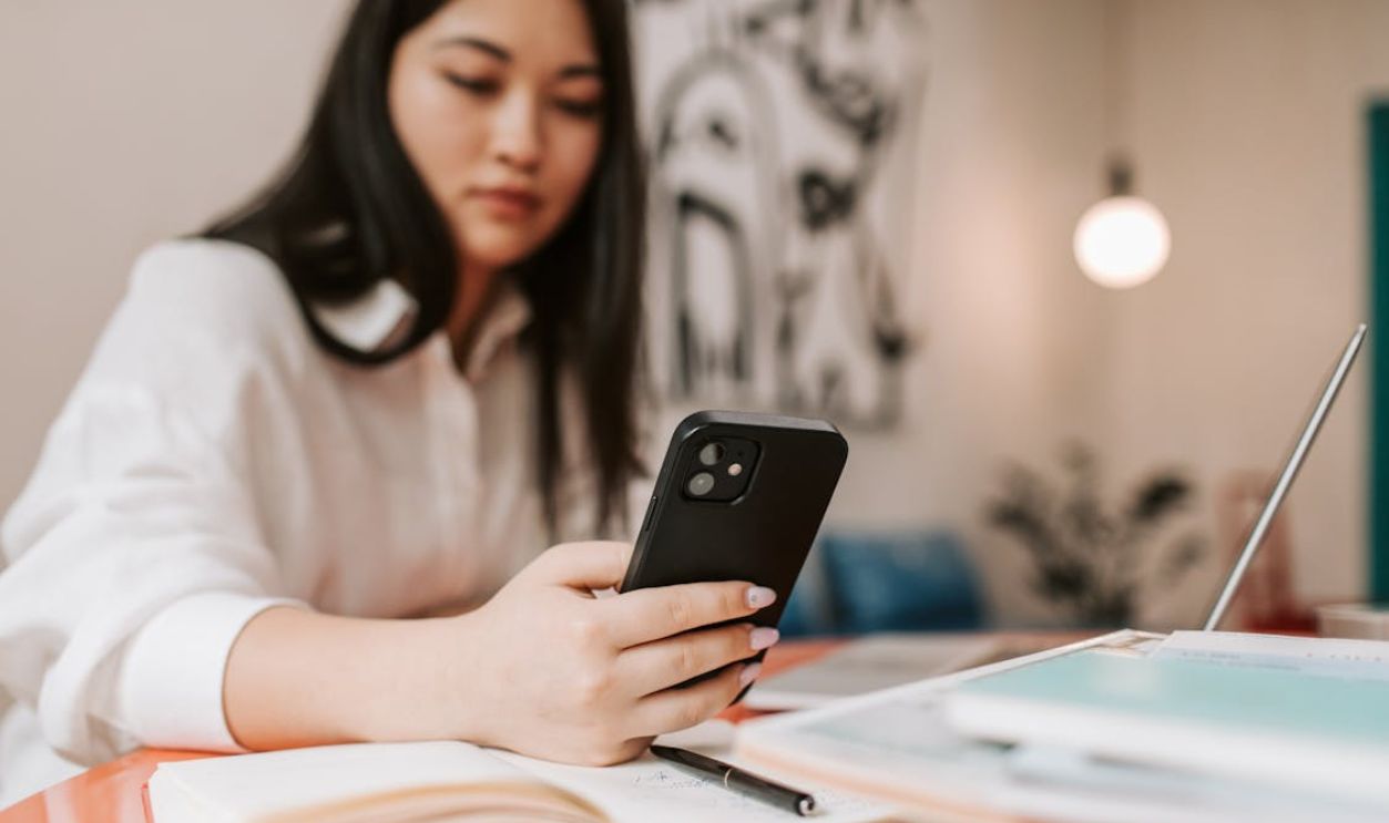 Woman in White Shirt Holding Black Smartphone