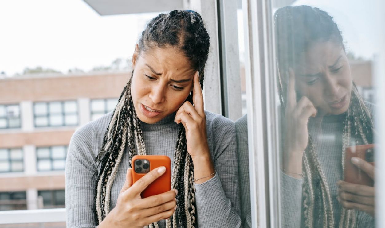 Tired black woman browsing mobile phone