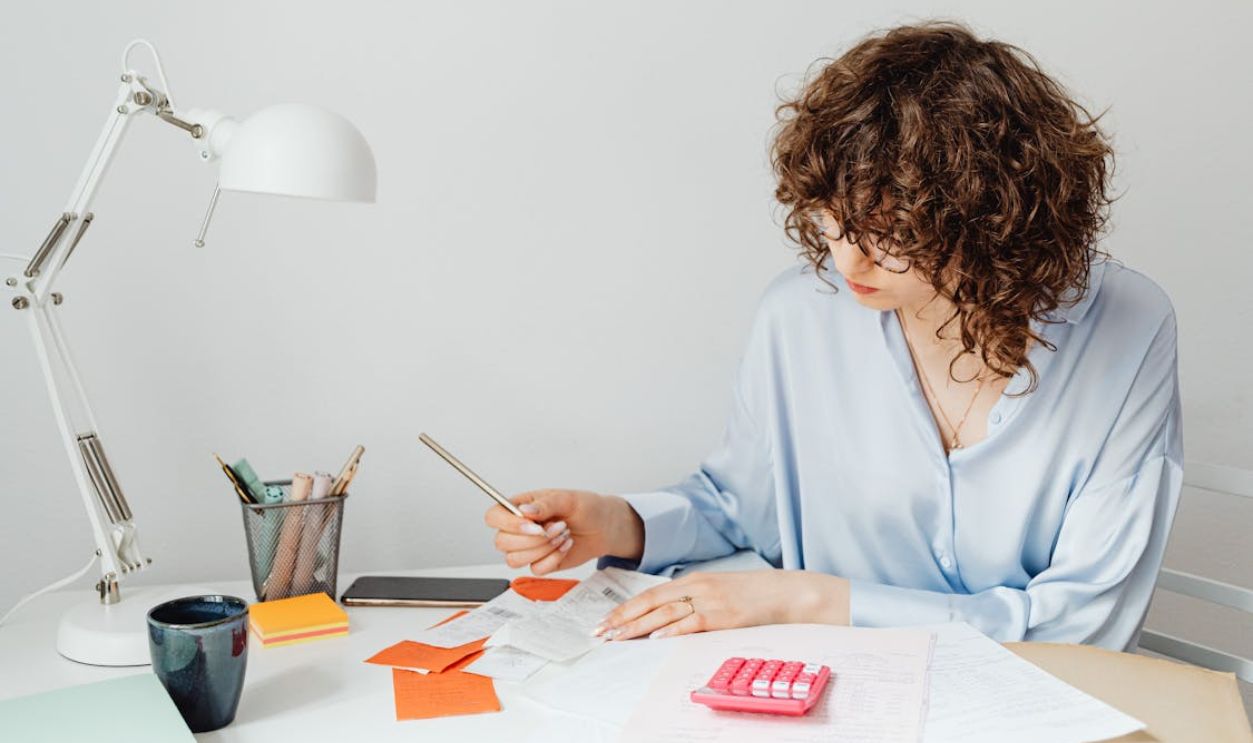 Woman Checking Receipts on Wooden Table