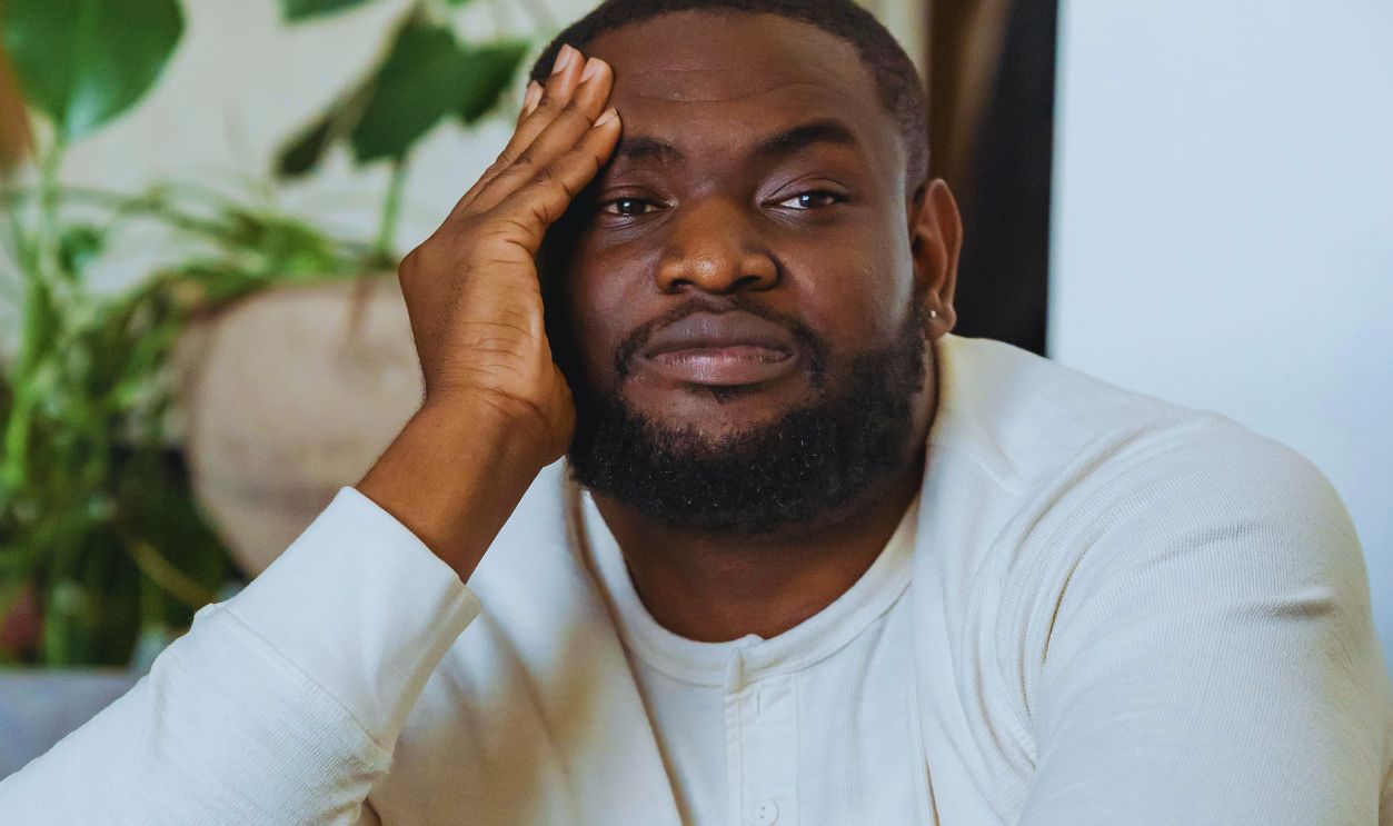 Tired black man leaning on hand and looking away