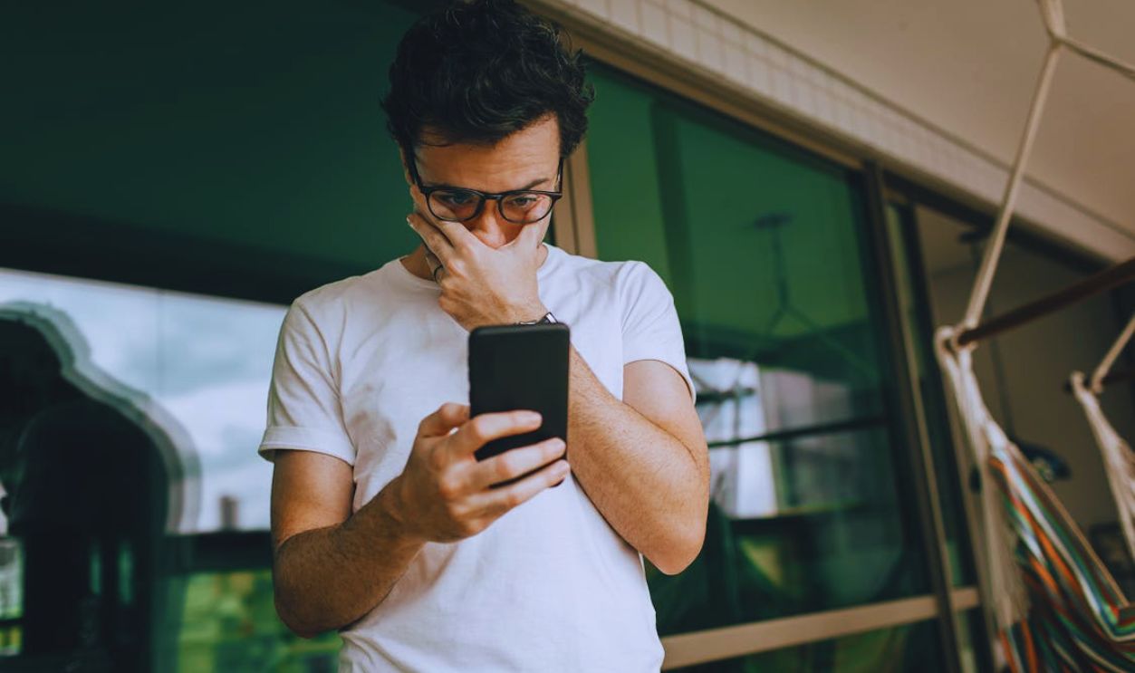 Man Looking at Phone with Hand on Face