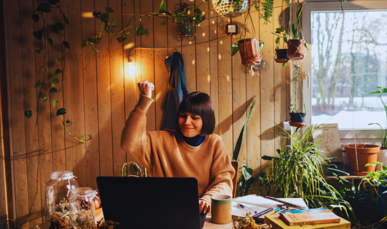 Woman Raising Her Fist and Using a Laptop