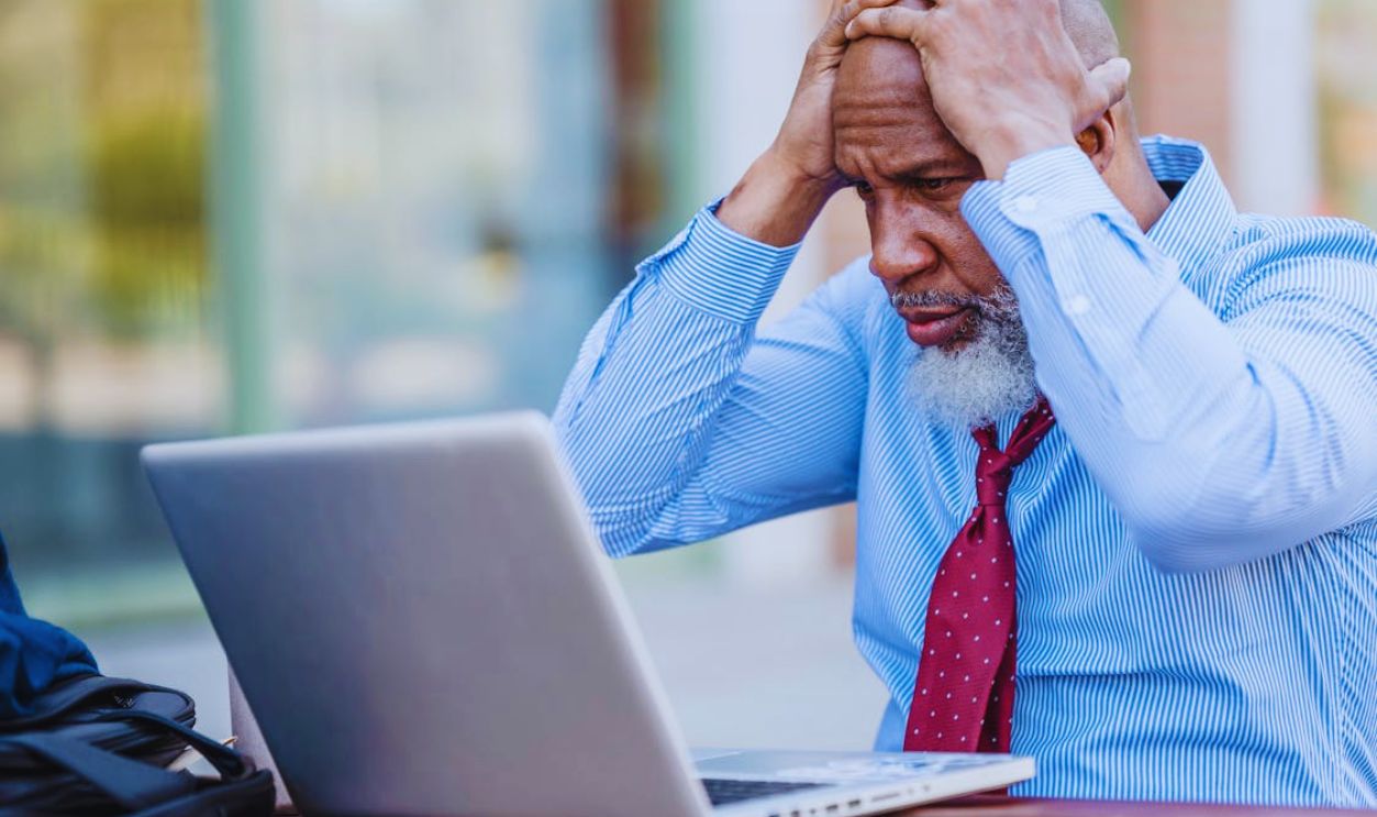 Stressed beard black man working on laptop