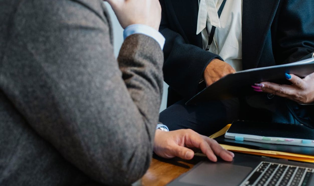 Crop female employee pointing at document while working in office with male colleague