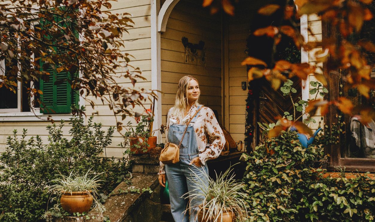 Glad woman standing on modern cottage doorsteps
