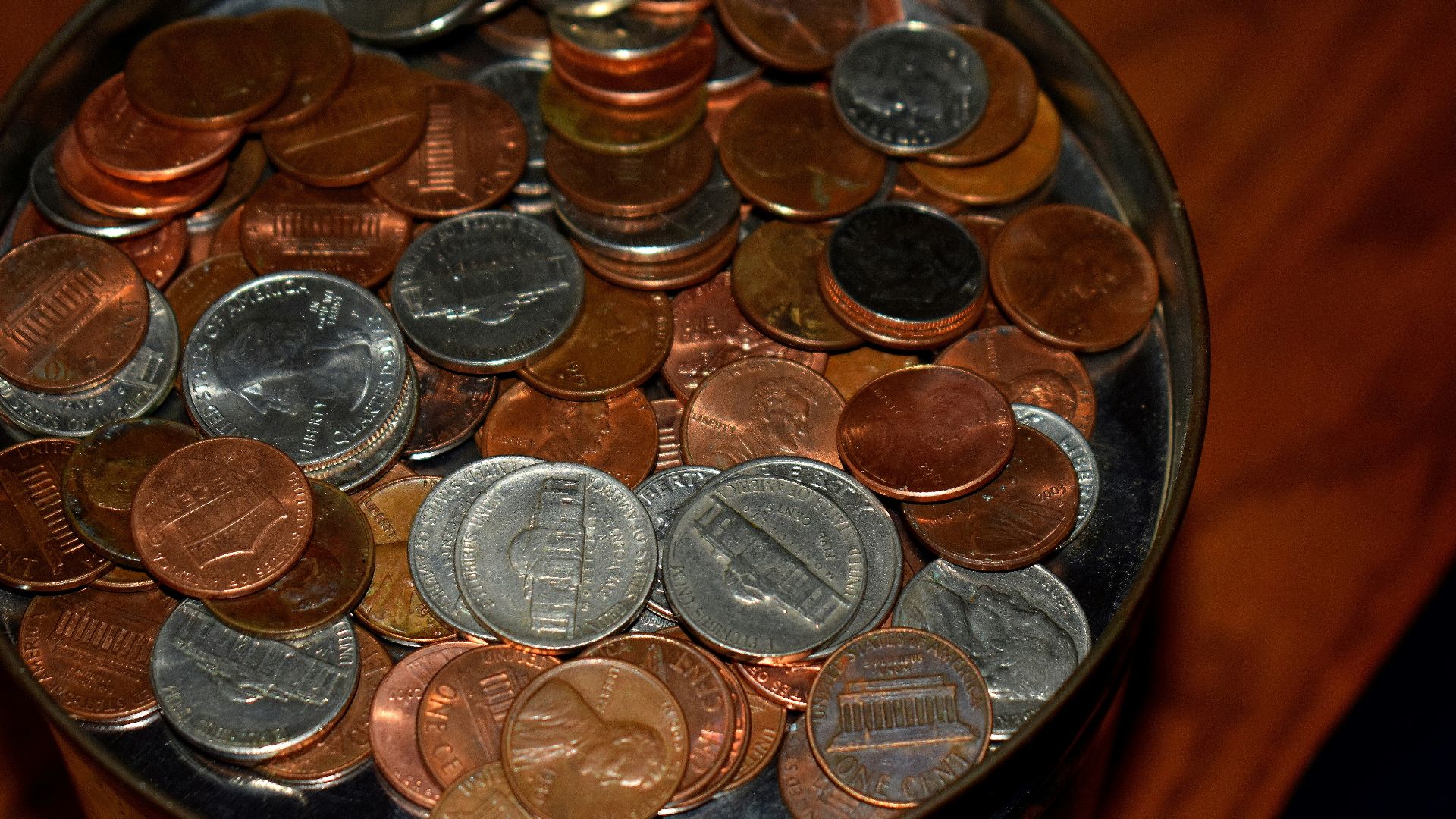 A close-up of a jar filled with pennies and nickels.