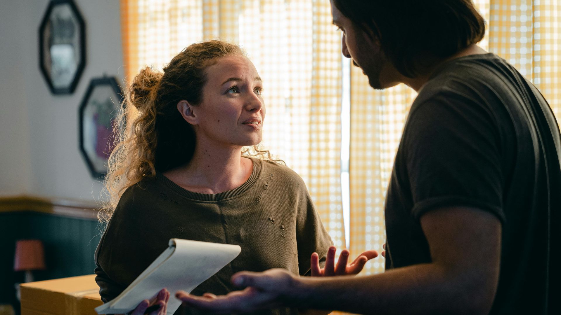 A couple talking in their living room surrounded by moving boxes, planning their new home setup.
