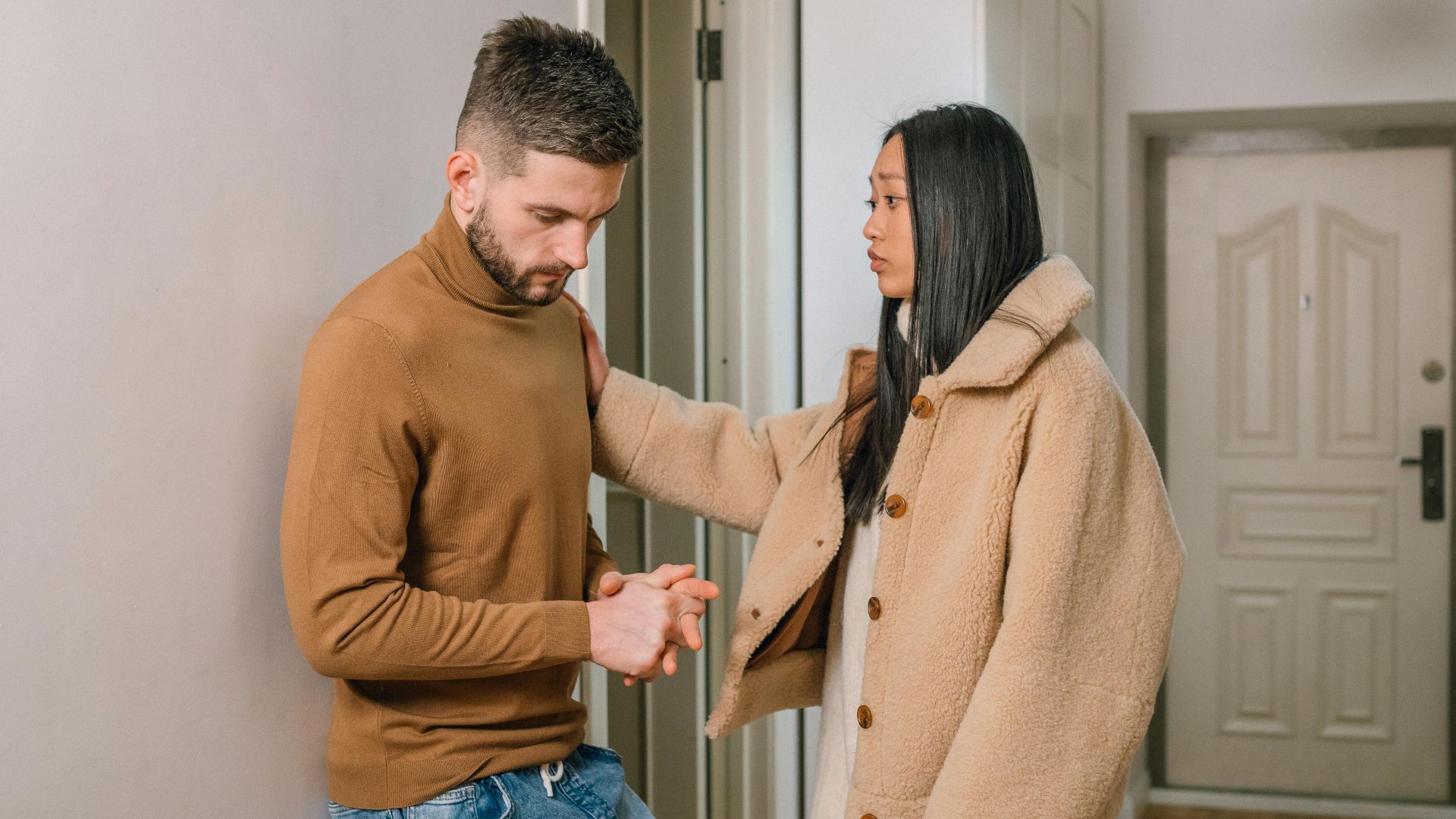 An interracial couple engaged in a serious conversation inside a home, showcasing emotion and connection.