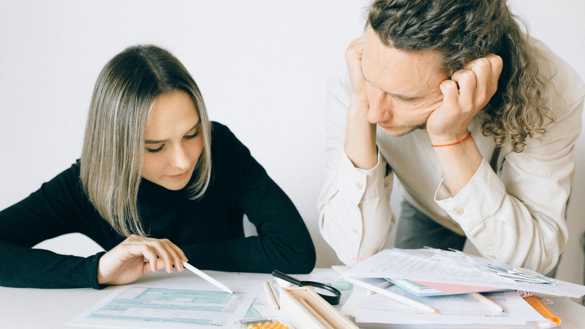 Two colleagues discussing paperwork in a modern office setting.