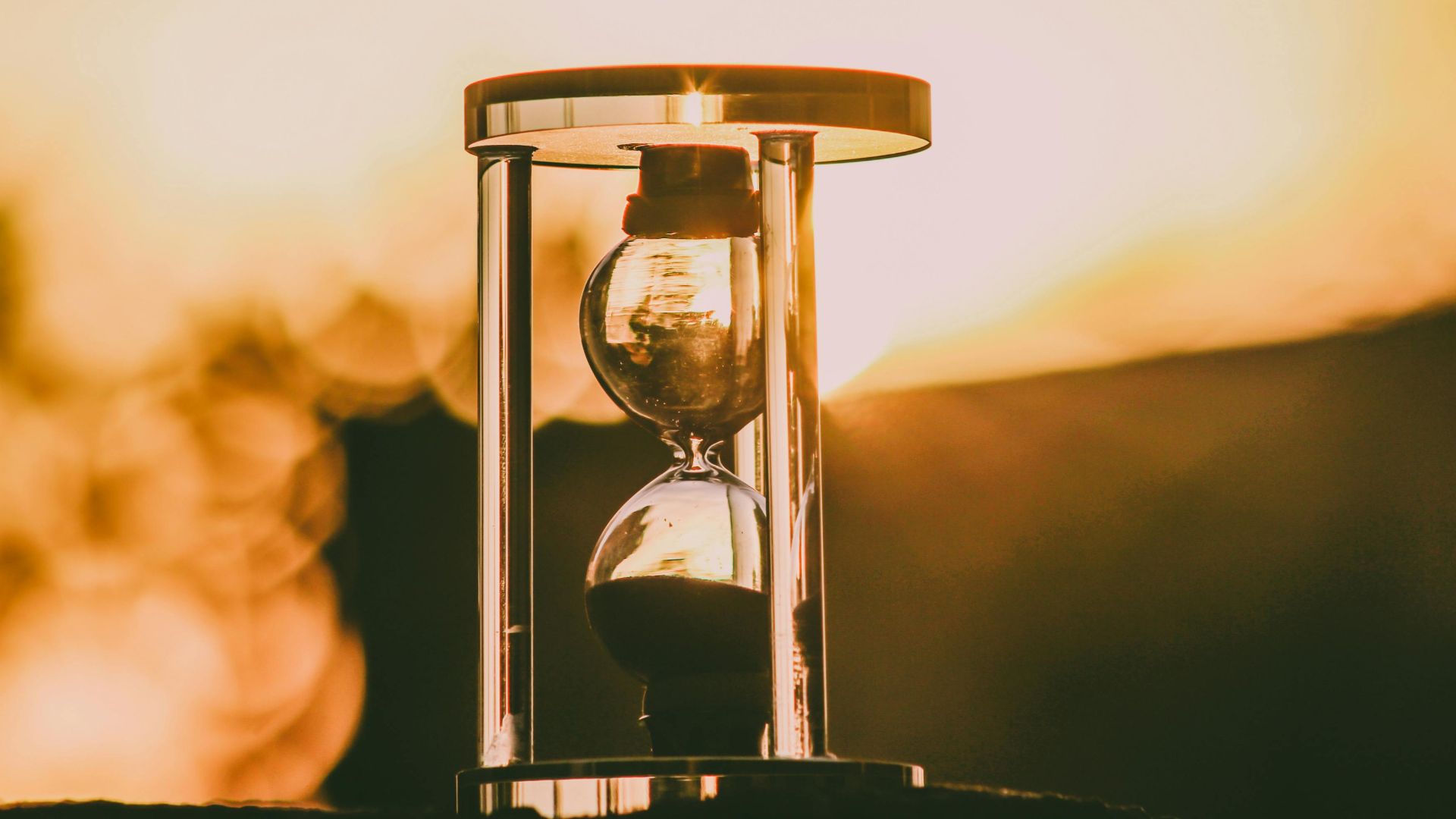 Close-up of an hourglass capturing the essence of time against a sunset backdrop.