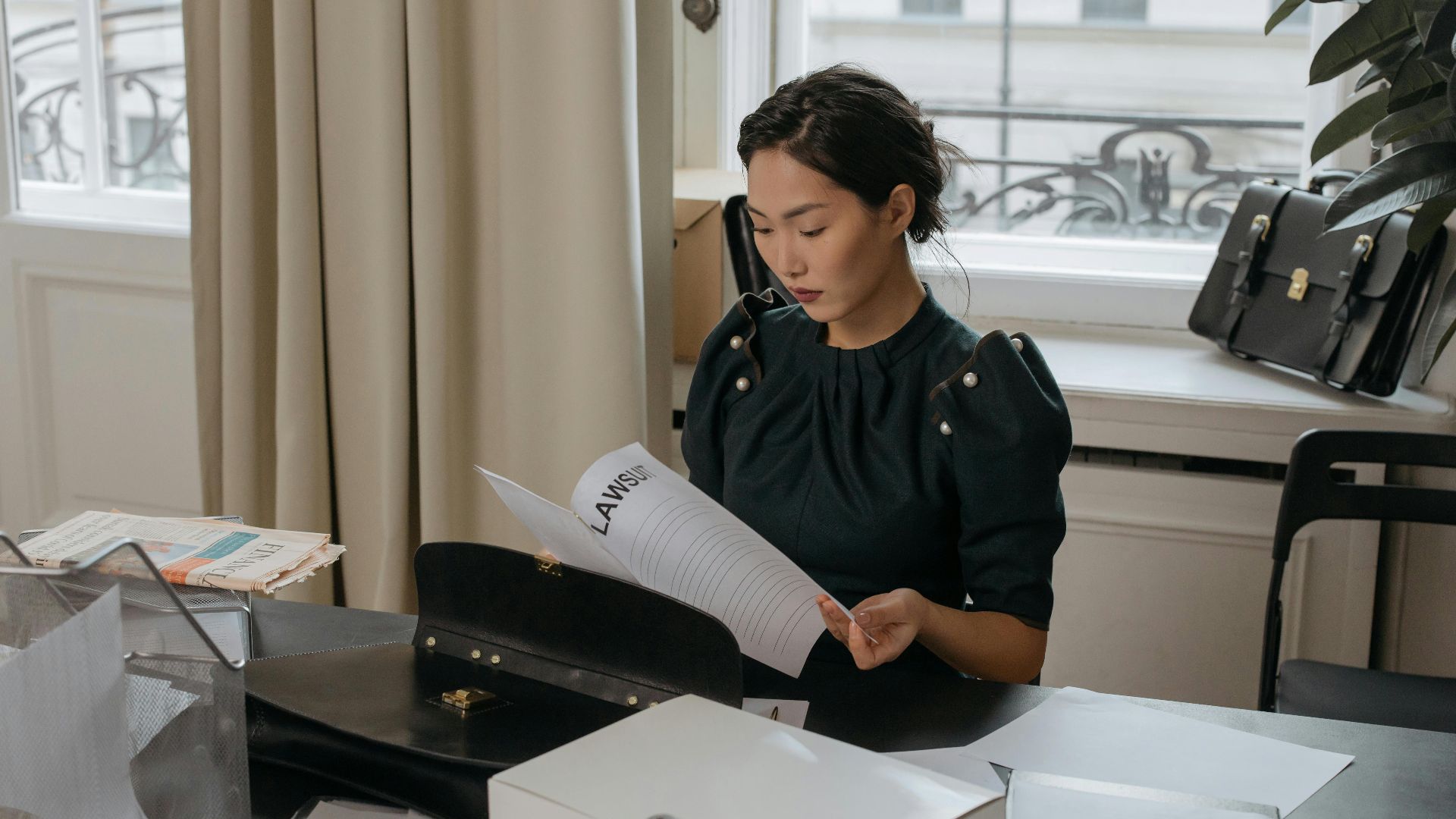 Elegant young woman reading documents in a stylish office setting.