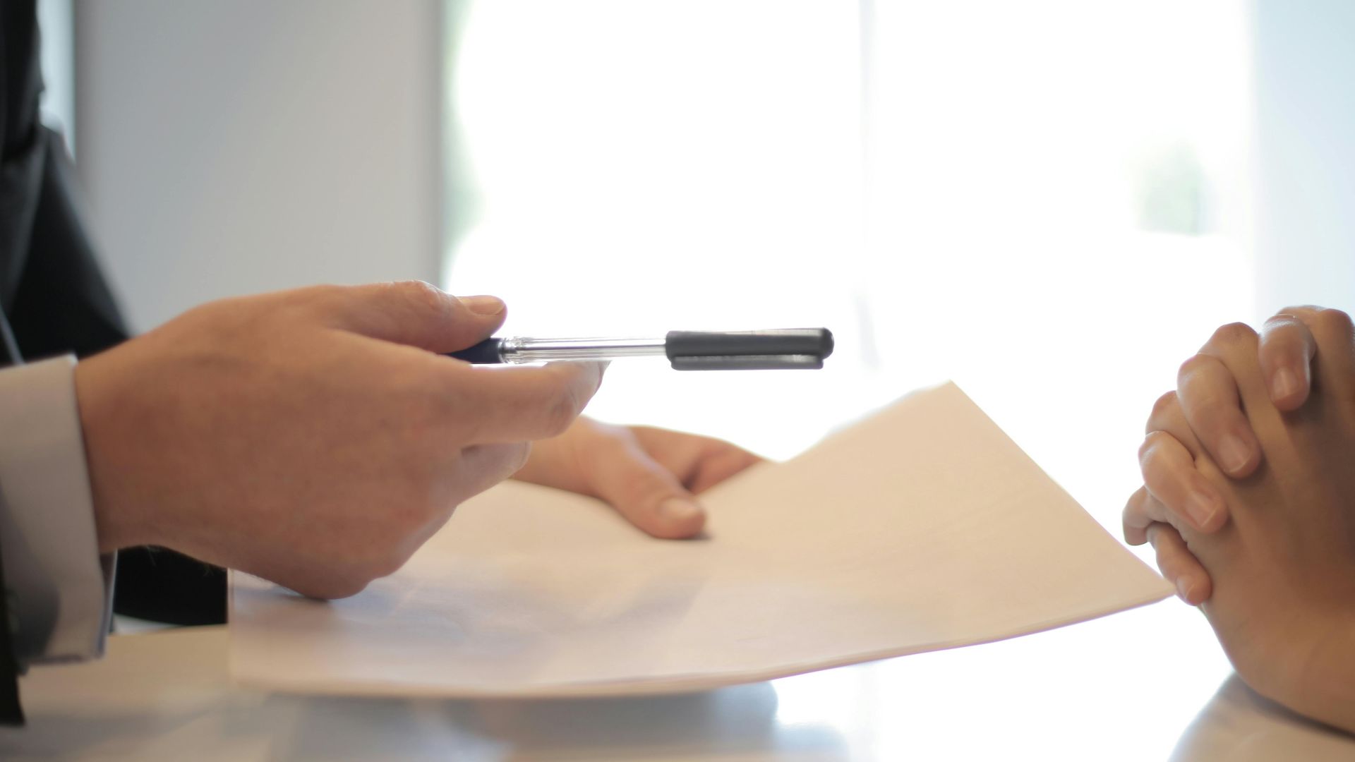 Close-up of a contract signing with hands over documents. Professional business interaction.