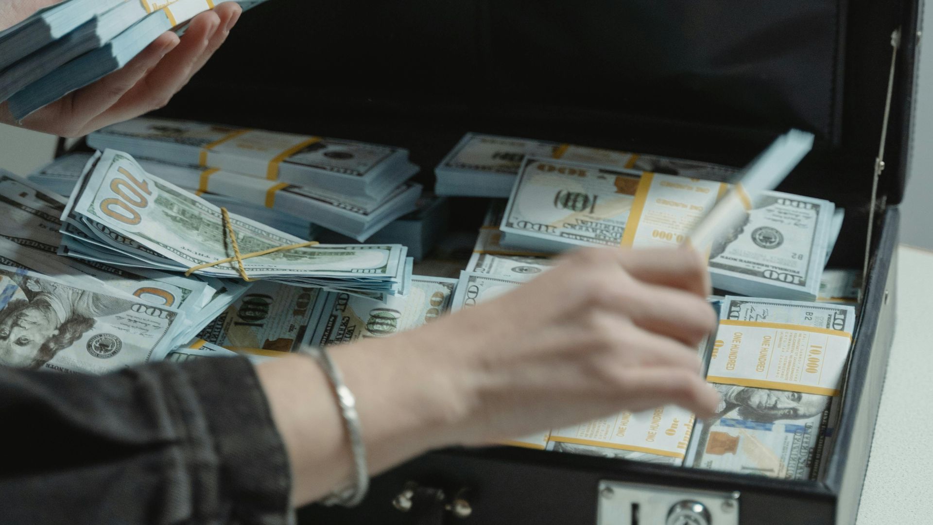 Close-up of organized bundles of cash in an open briefcase being handled.