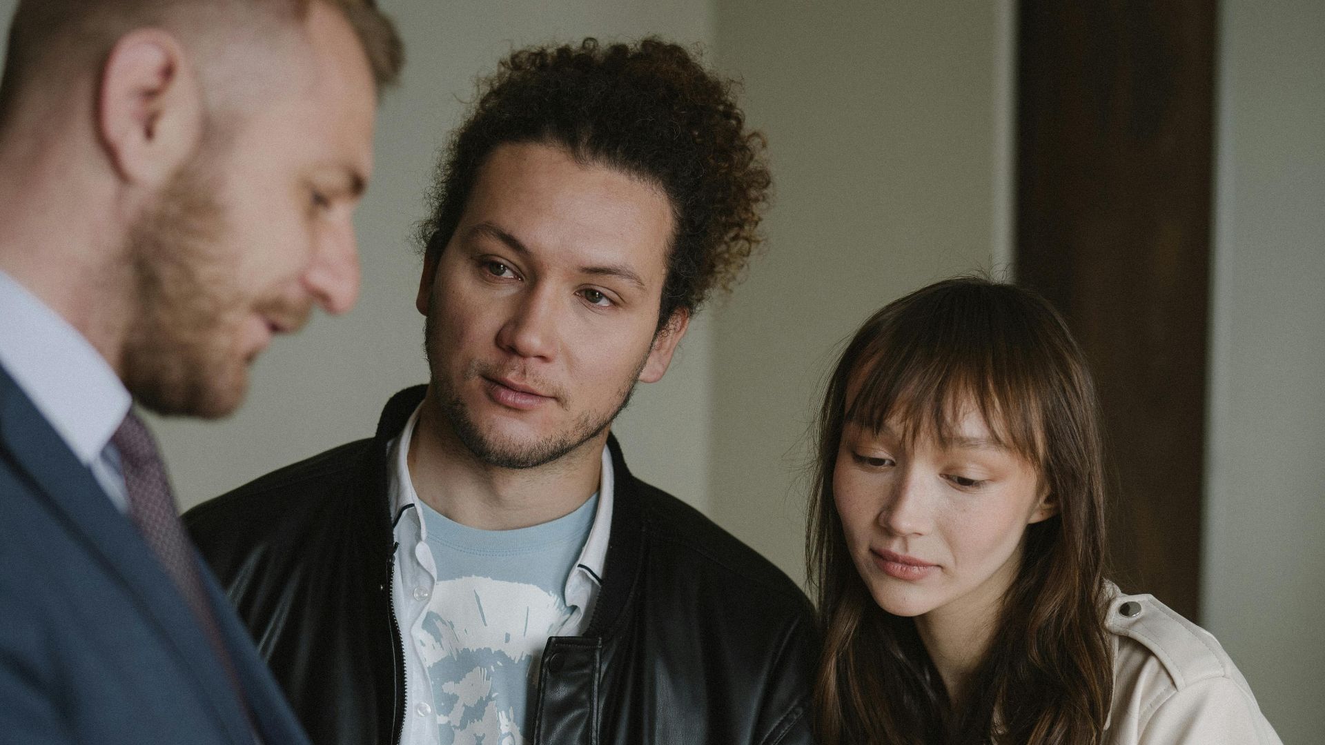 A real estate agent conversing with a potential client couple inside a modern home.