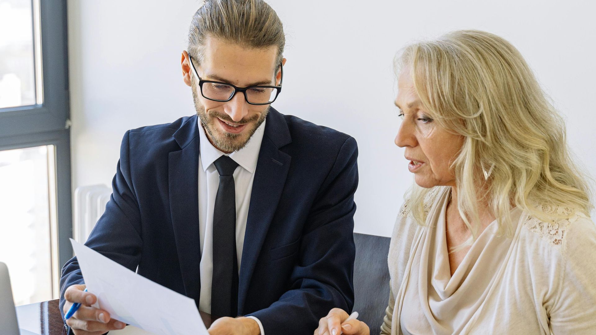 Two business professionals reviewing financial documents and graphs during a meeting.