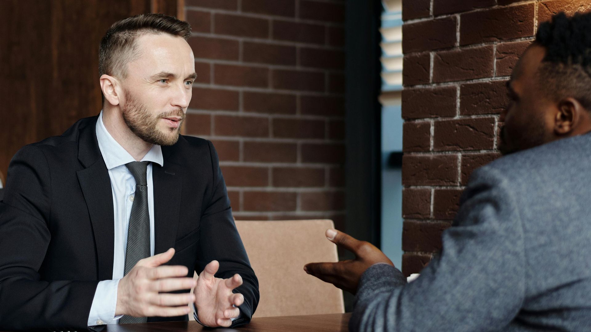 Businessmen engaged in a professional conversation in a stylish café setting.