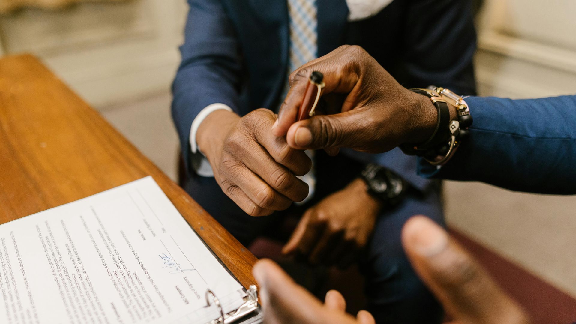 Two businessmen in suits finalize a contract, highlighting teamwork and agreement.