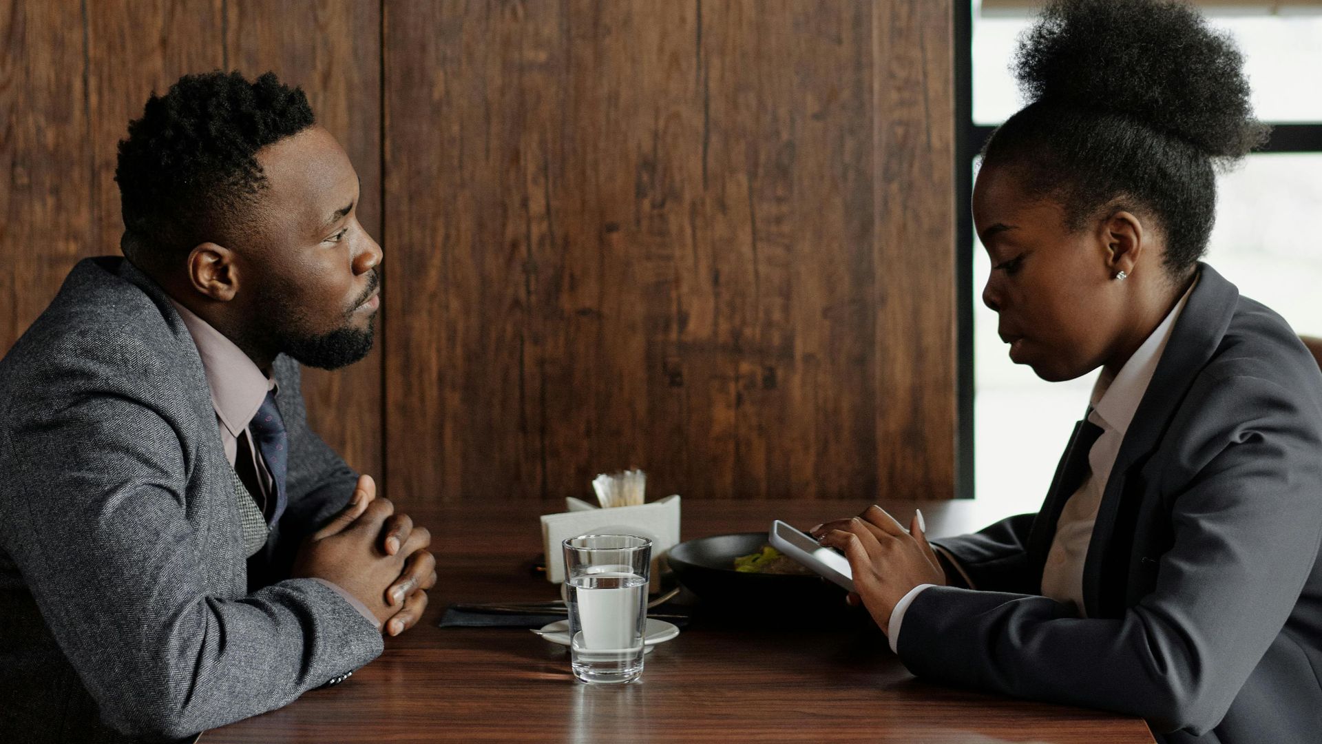 Professional coworkers discussing work over coffee in a café setting.