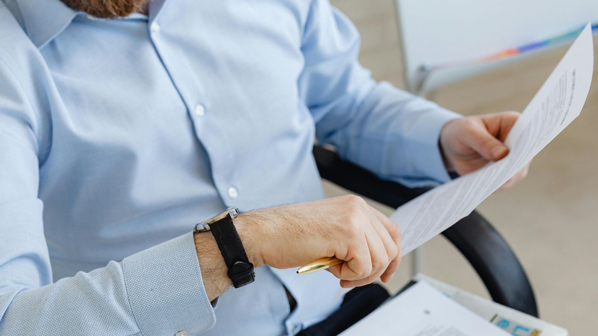 Businessman reviewing papers in office setting, highlighting analysis and attention to detail.
