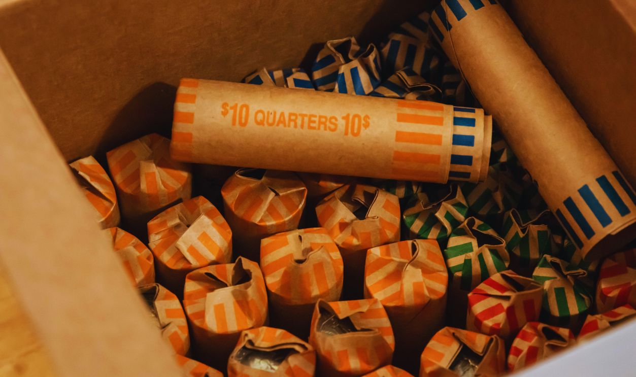 American currency coins rolled up into coin rollers. Savings being prepared for bank deposit. Quarters, dimes, nickles and pennies. Dollars.