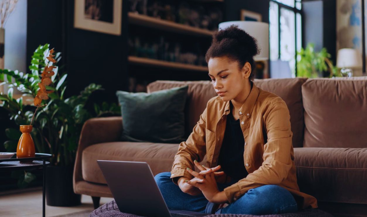 A Woman Sitting on a Bean Bag while Looking at the Screen of a Laptop