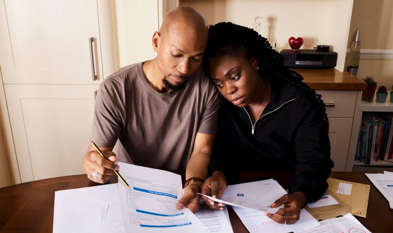 Couple Sitting by Table Looking through Bills