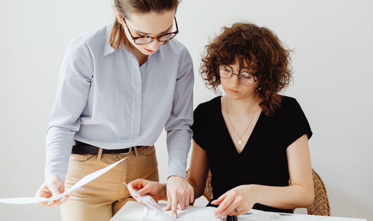 Two Women Looking at White Paper