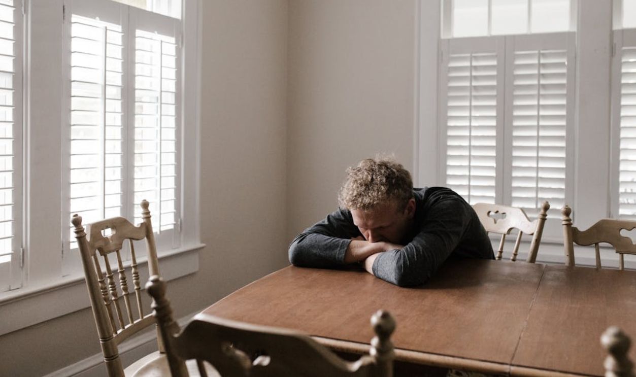 Man in Gray Long Sleeve Shirt Sitting on Brown Wooden Chair