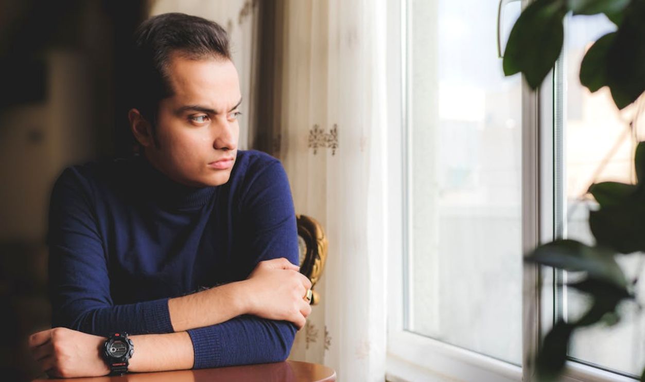 Man in Blue Sweater Looking Out the Window