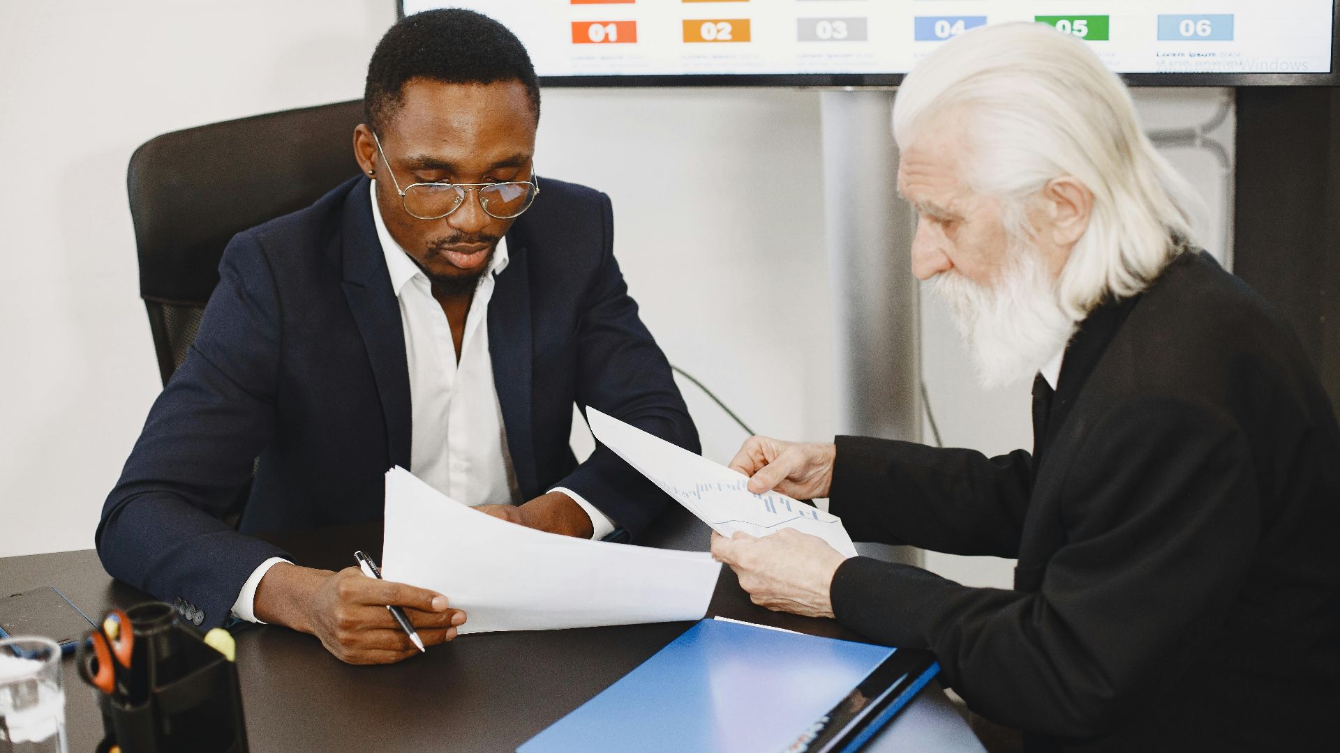 Two businessmen in a meeting discussing documents, focusing on a diverse team engagement.