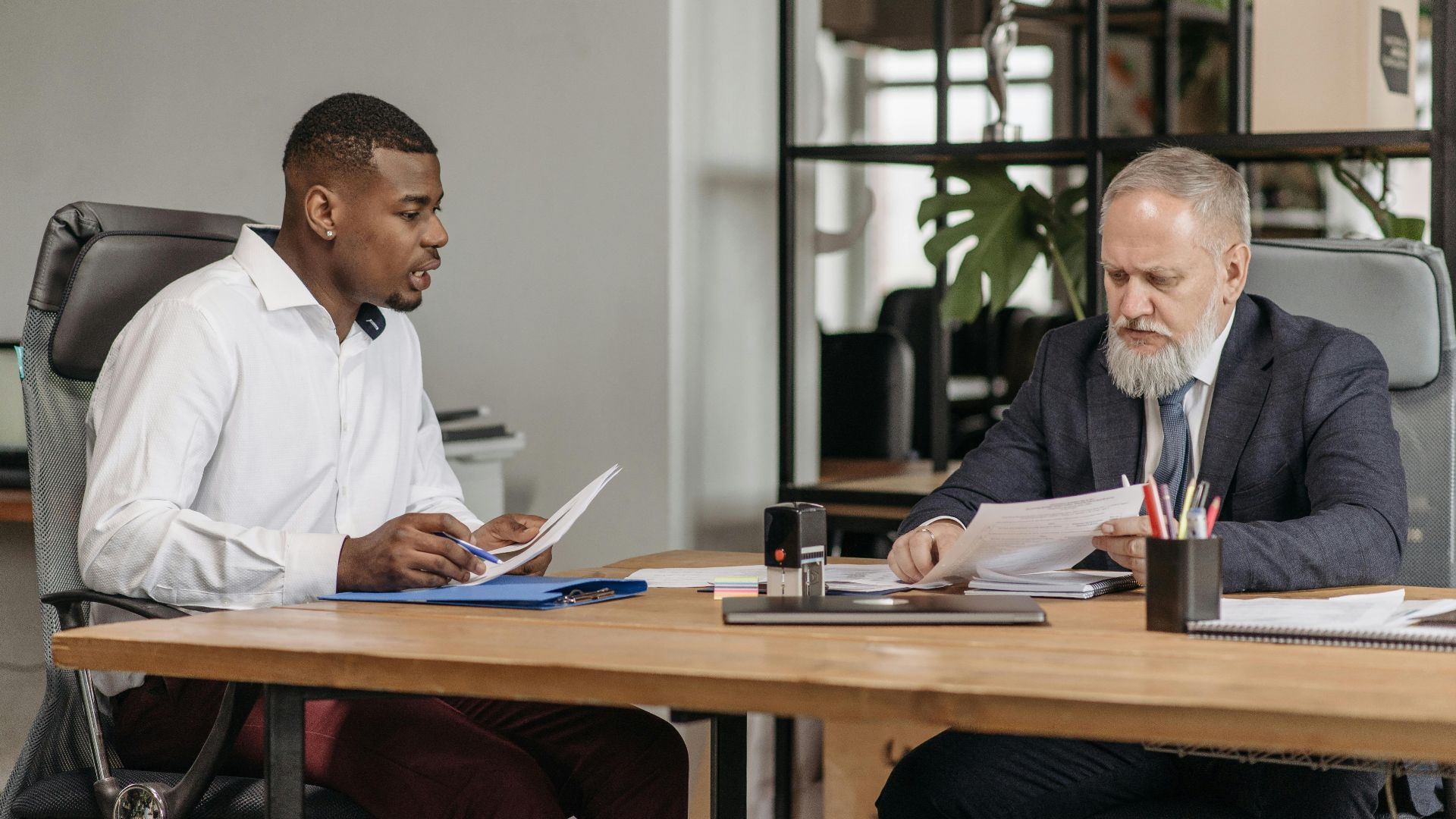 Two businessmen discussing documents during a meeting in a modern office.