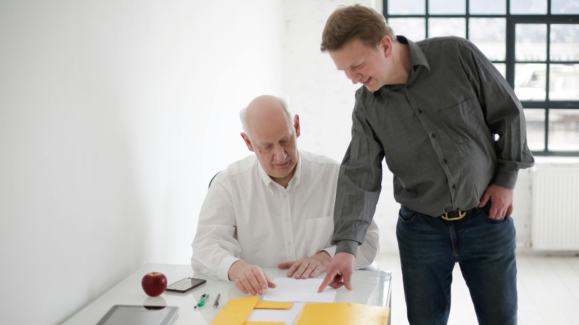 Two men reviewing documents in a bright, modern office setting. Collaboration and teamwork.