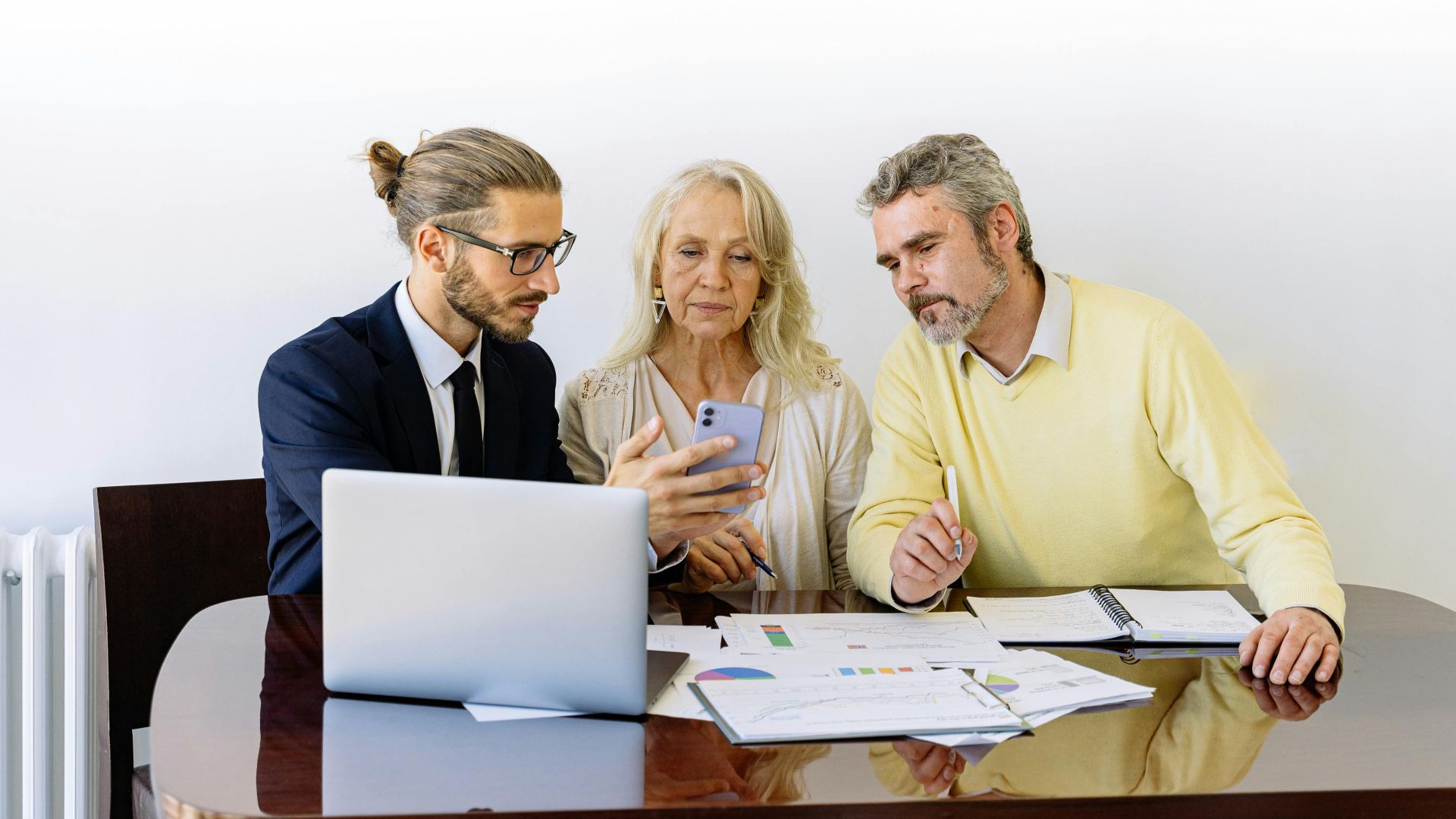 Three individuals collaborating on financial documents during a business meeting.