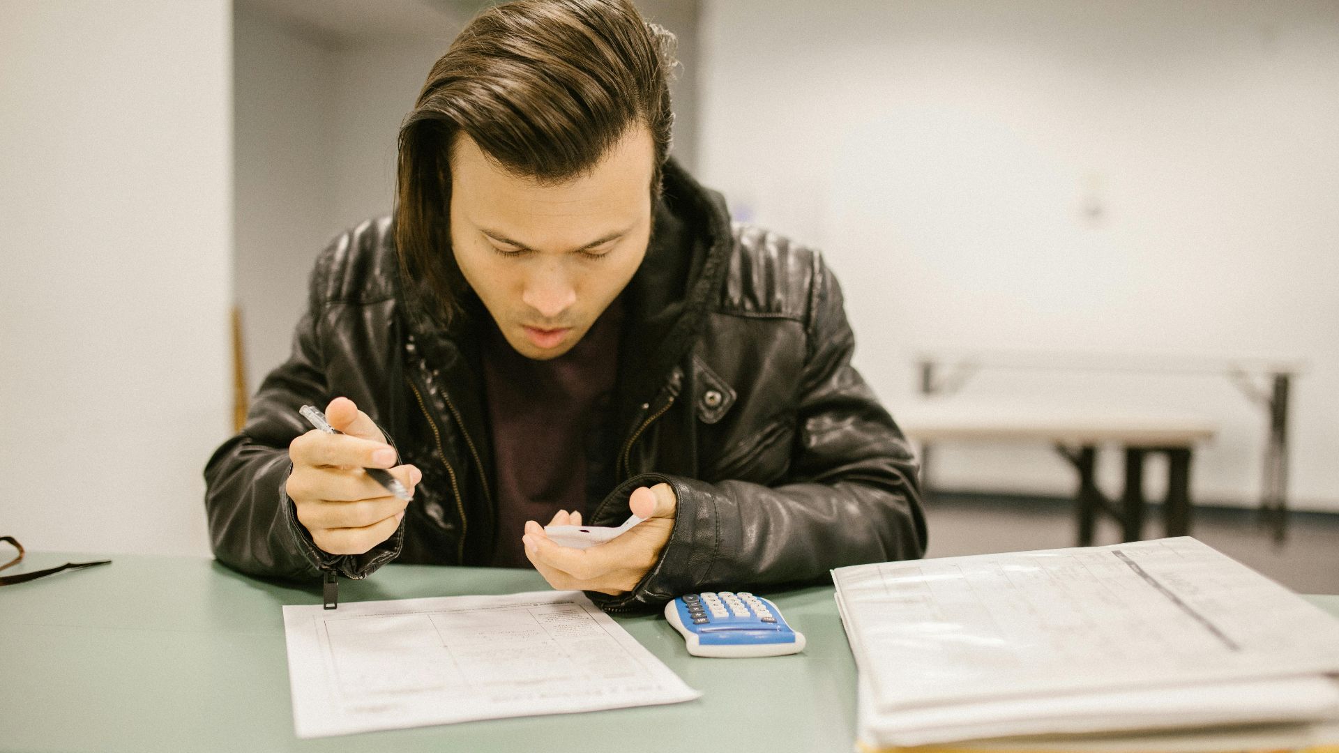 A male student in a classroom studying for an exam with a focus on his notes.