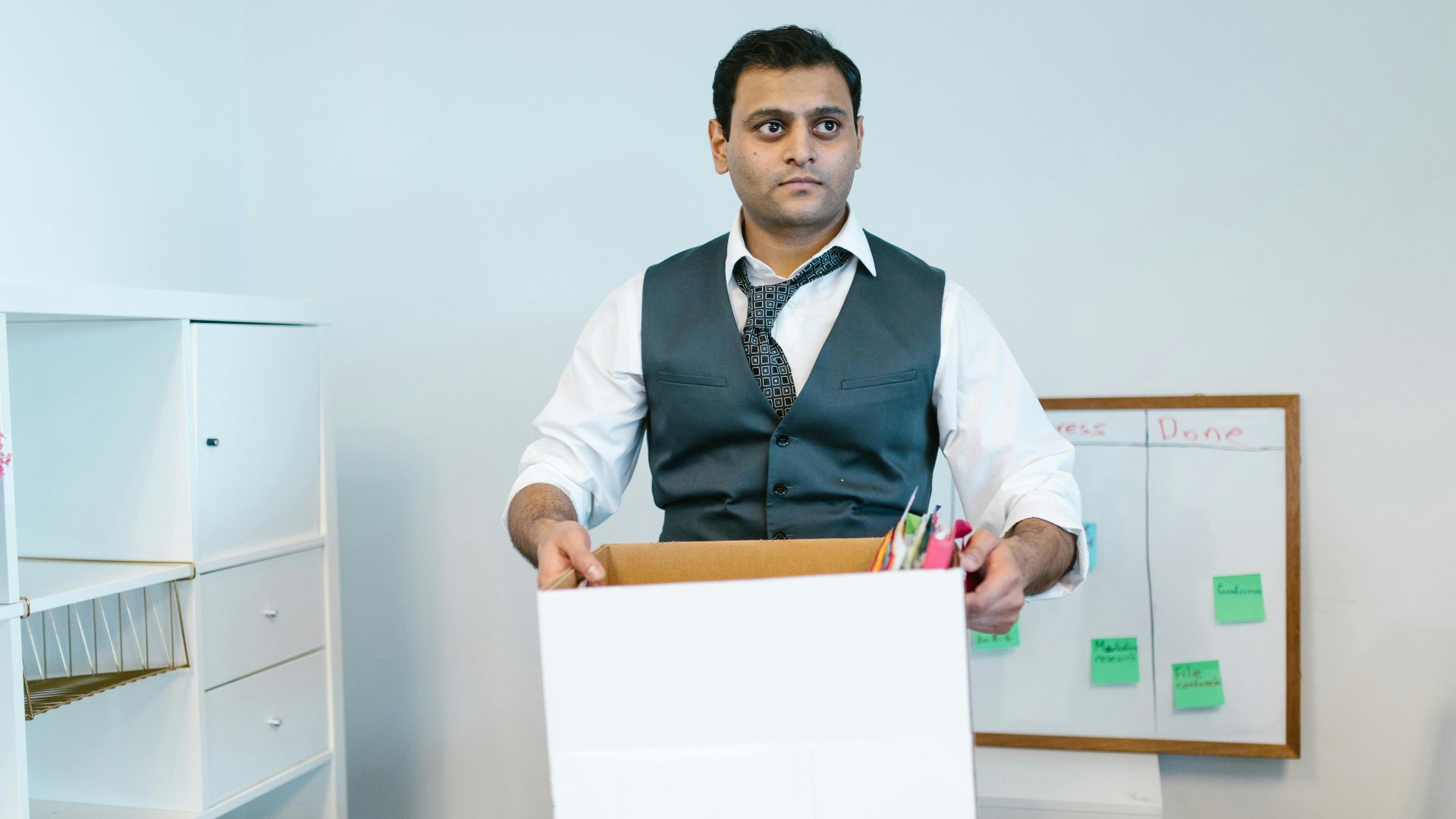 Professional man organizing office belongings in a cardboard box, preparing for transition.