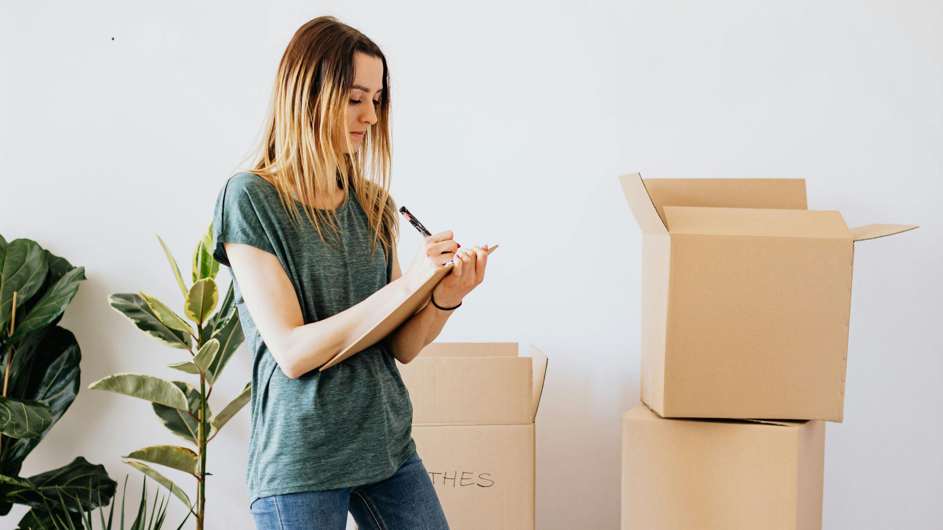 A woman organizes cardboard boxes while moving into a new house.